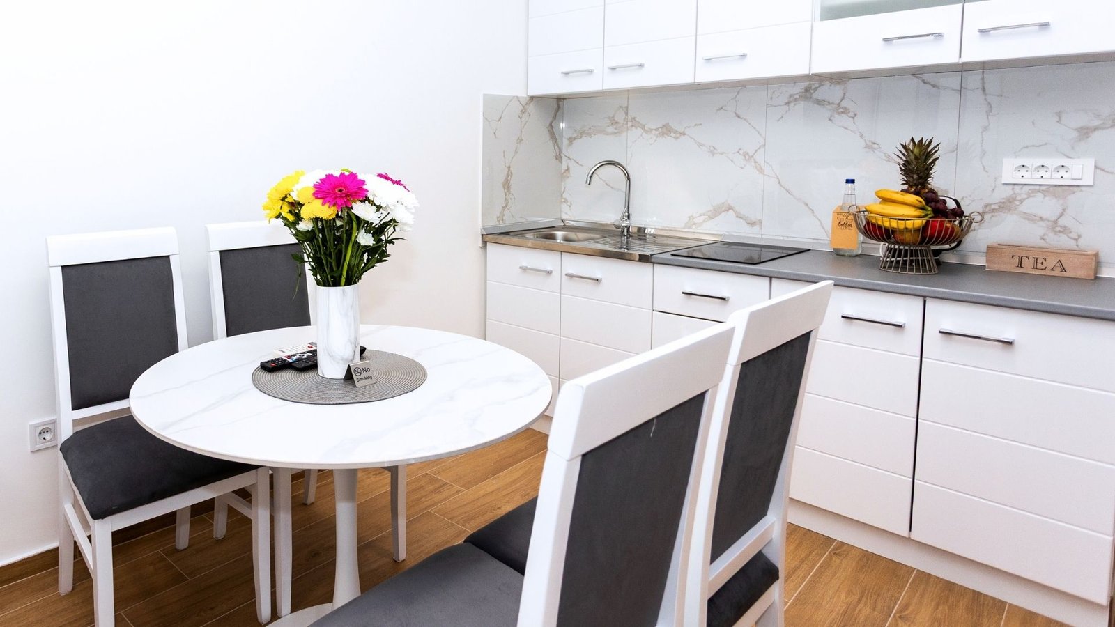 Dining area with round table and fresh flowers in studio apartment Herceg Novi